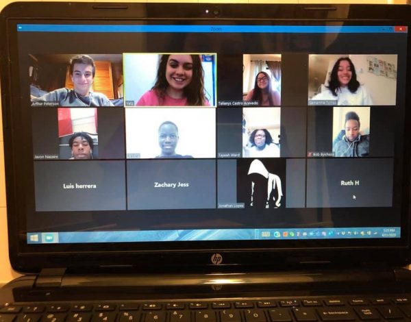 A laptop screen displays a video call with twelve participants in a grid. Some are smiling, fostering a friendly and engaged atmosphere.