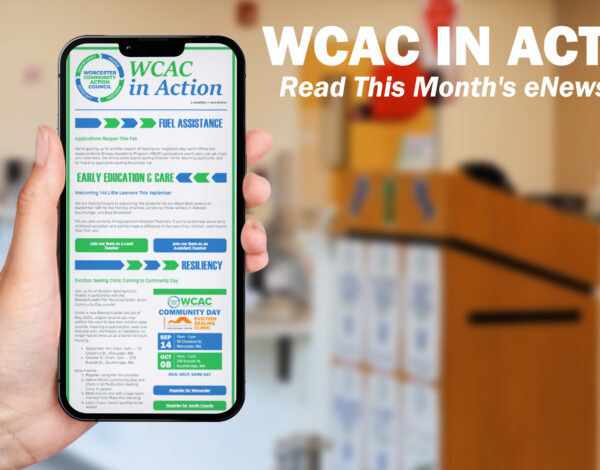 A hand holds up a smartphone displaying the "WCAC in Action" monthly eNewsletter, with sections on Fuel Assistance, Early Education & Care, and Resiliency visible on screen. To the right, bold white text reads "WCAC in Action: Read This Month's eNewsletter!" against a blurred background of a community office space with a wooden podium.