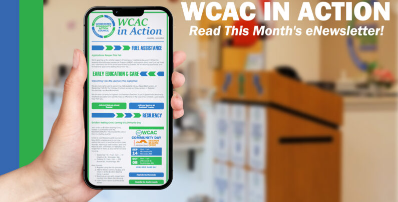 A hand holds up a smartphone displaying the "WCAC in Action" monthly eNewsletter, with sections on Fuel Assistance, Early Education & Care, and Resiliency visible on screen. To the right, bold white text reads "WCAC in Action: Read This Month's eNewsletter!" against a blurred background of a community office space with a wooden podium.