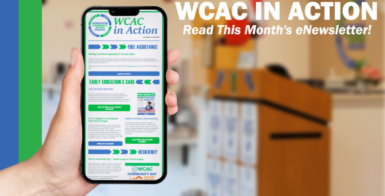 A hand holds up a smartphone displaying the "WCAC in Action" monthly eNewsletter, with sections on Fuel Assistance, Early Education & Care, and Resiliency visible on screen. To the right, bold white text reads "WCAC in Action: Read This Month's eNewsletter!" against a blurred background of a community office space with a wooden podium.